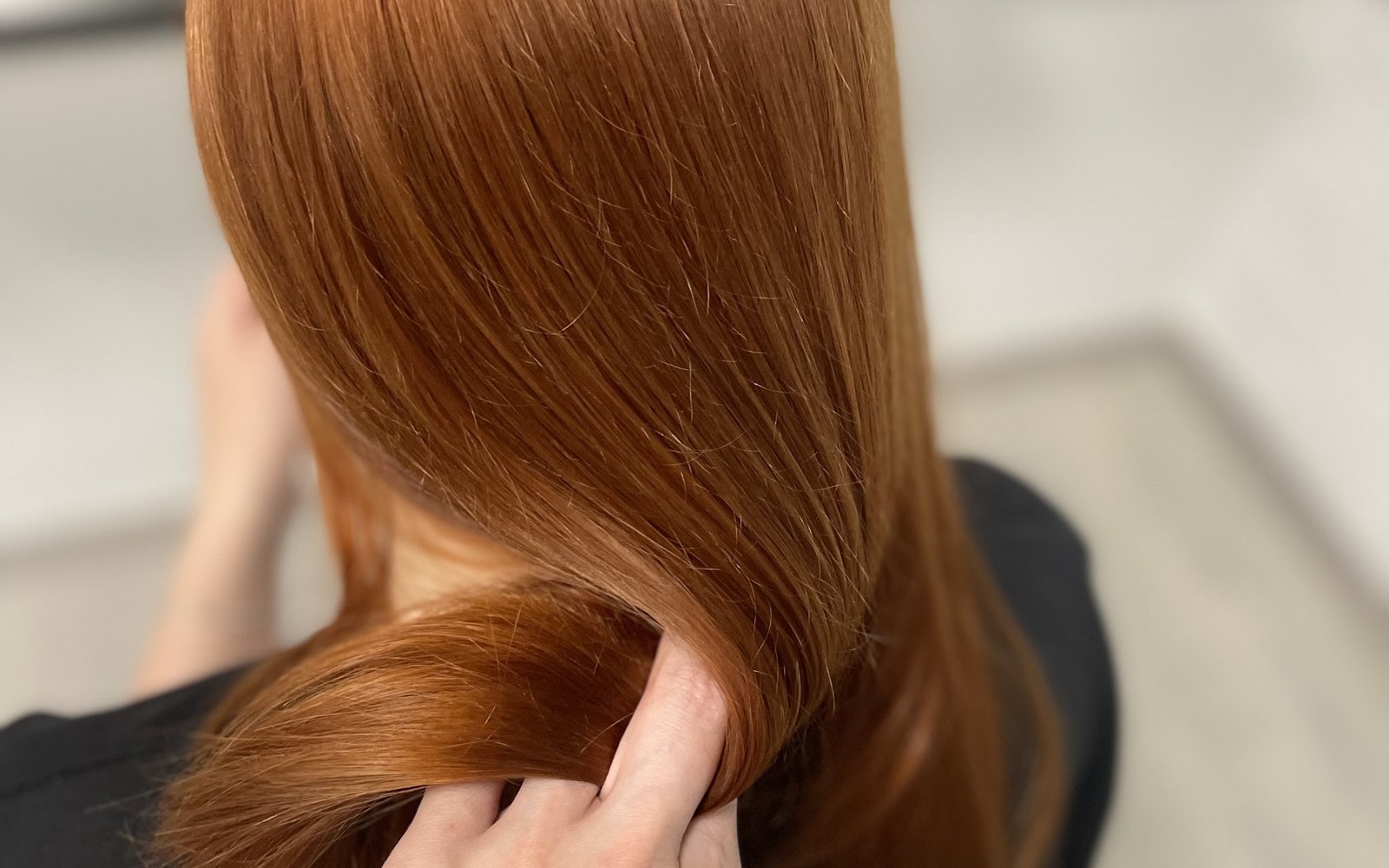 Lang, glanzend koperrood haar dat met één hand wordt opgetild