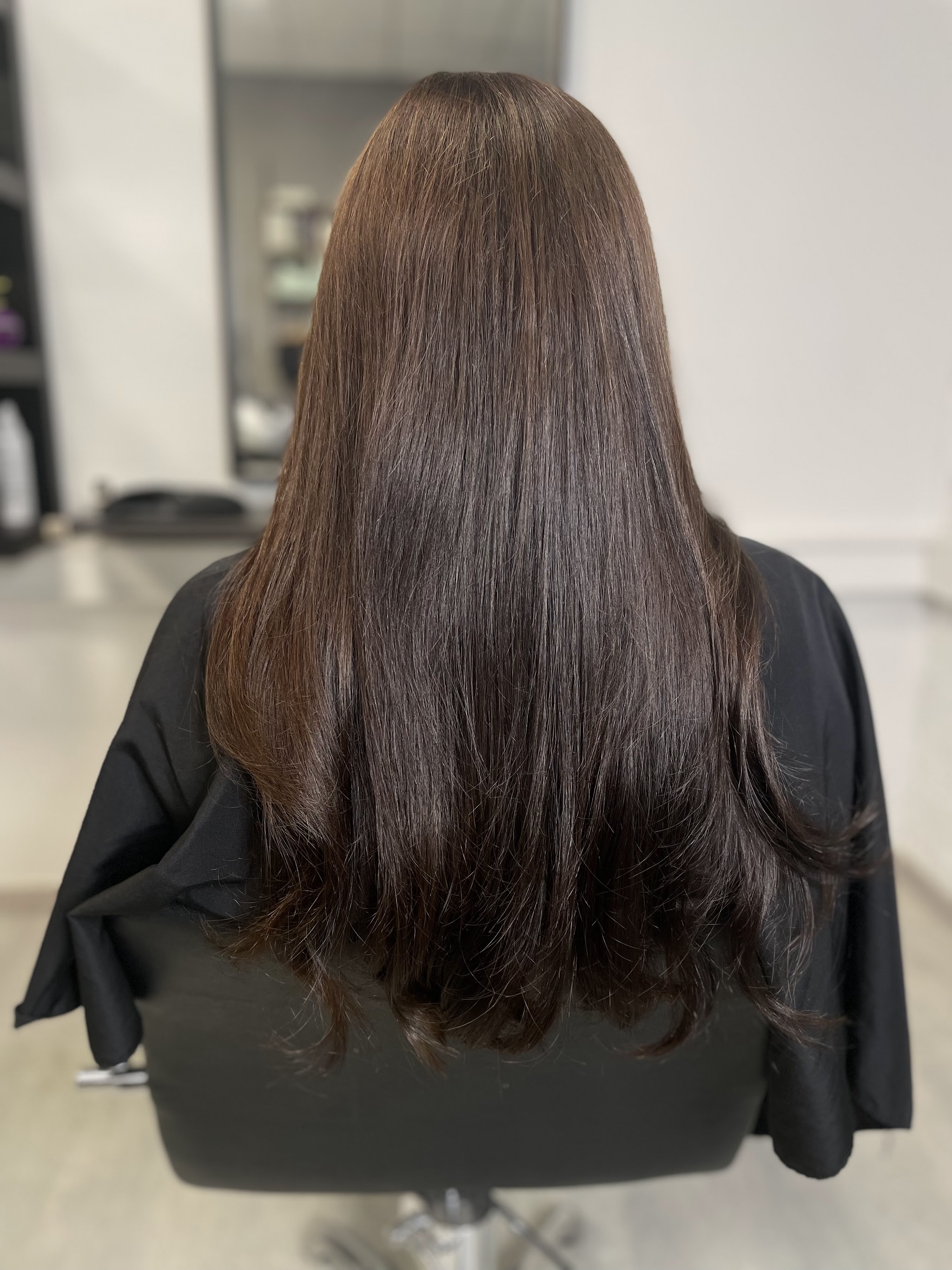 Lang warm donkerbruin haar in de salonstoel